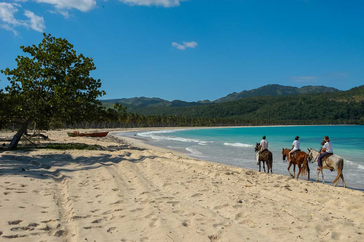 Visitors riding horses along the shore.