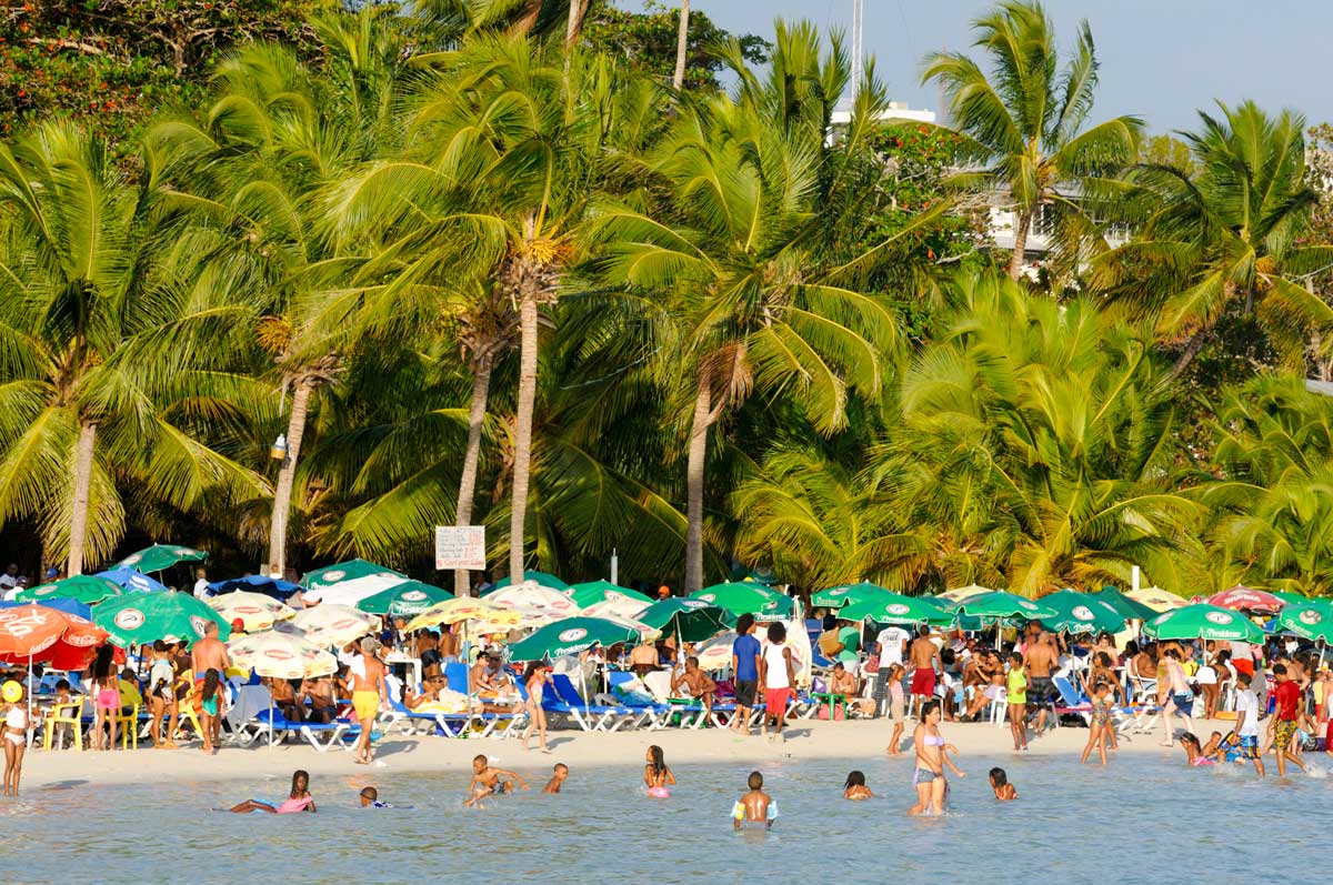 Beach full of umbrellas and people.